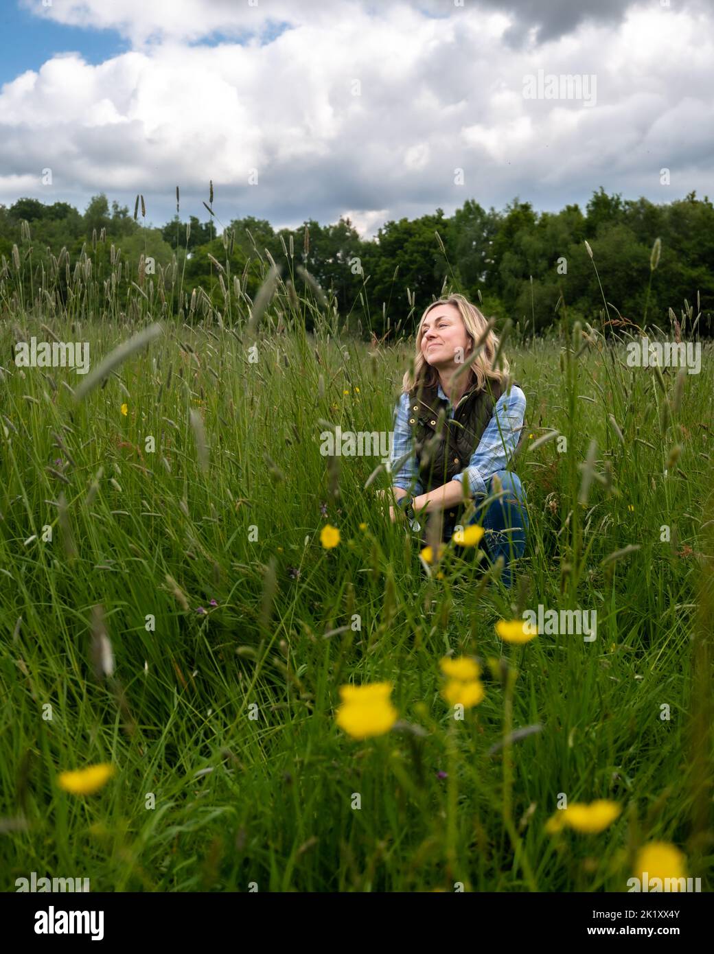Femme se relaxant dans la prairie parmi les fleurs et les herbes. Banque D'Images