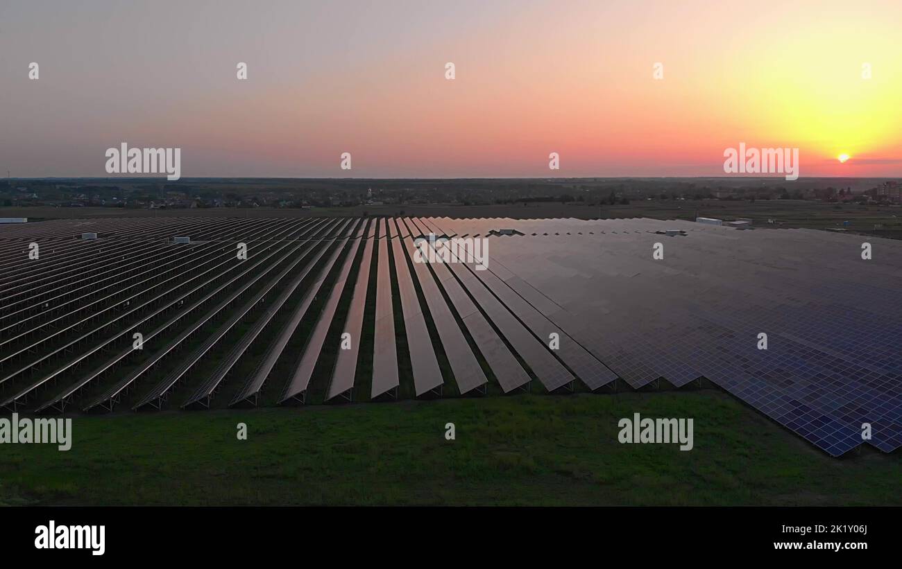 De grands panneaux solaires dans une ferme solaire au coucher du soleil d'été. Centrales solaires. Vidéo 4K, vue aérienne par drone Banque D'Images