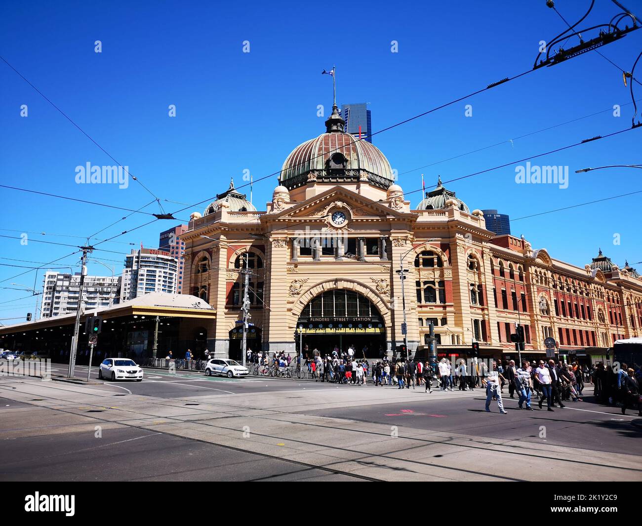 La gare de Flinders Street à Melbourne avec une foule de personnes dans la rue contre un ciel bleu Banque D'Images