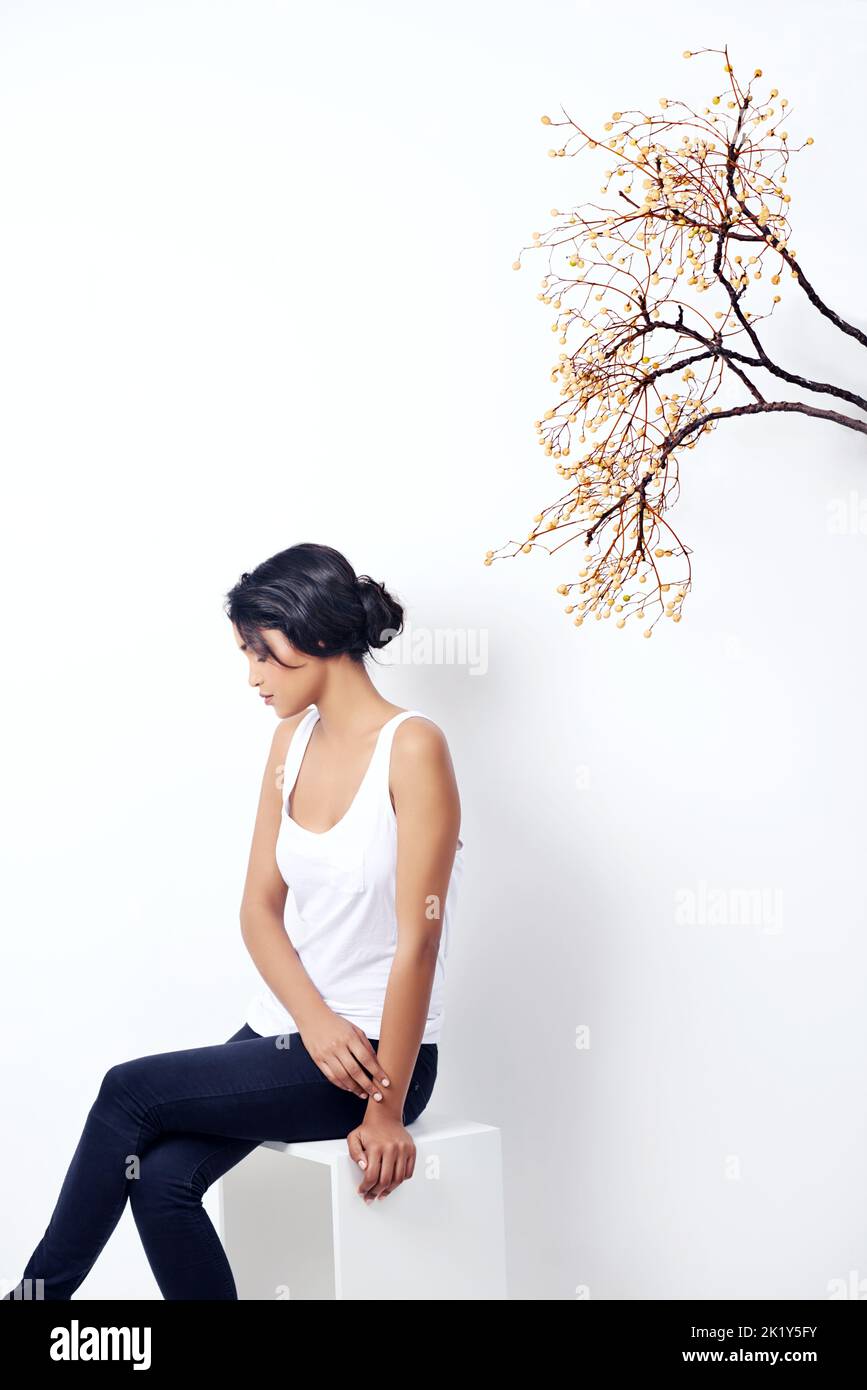Comme toujours comme nature. Studio photo d'une jeune femme ethnique attrayante assise sous une branche Banque D'Images