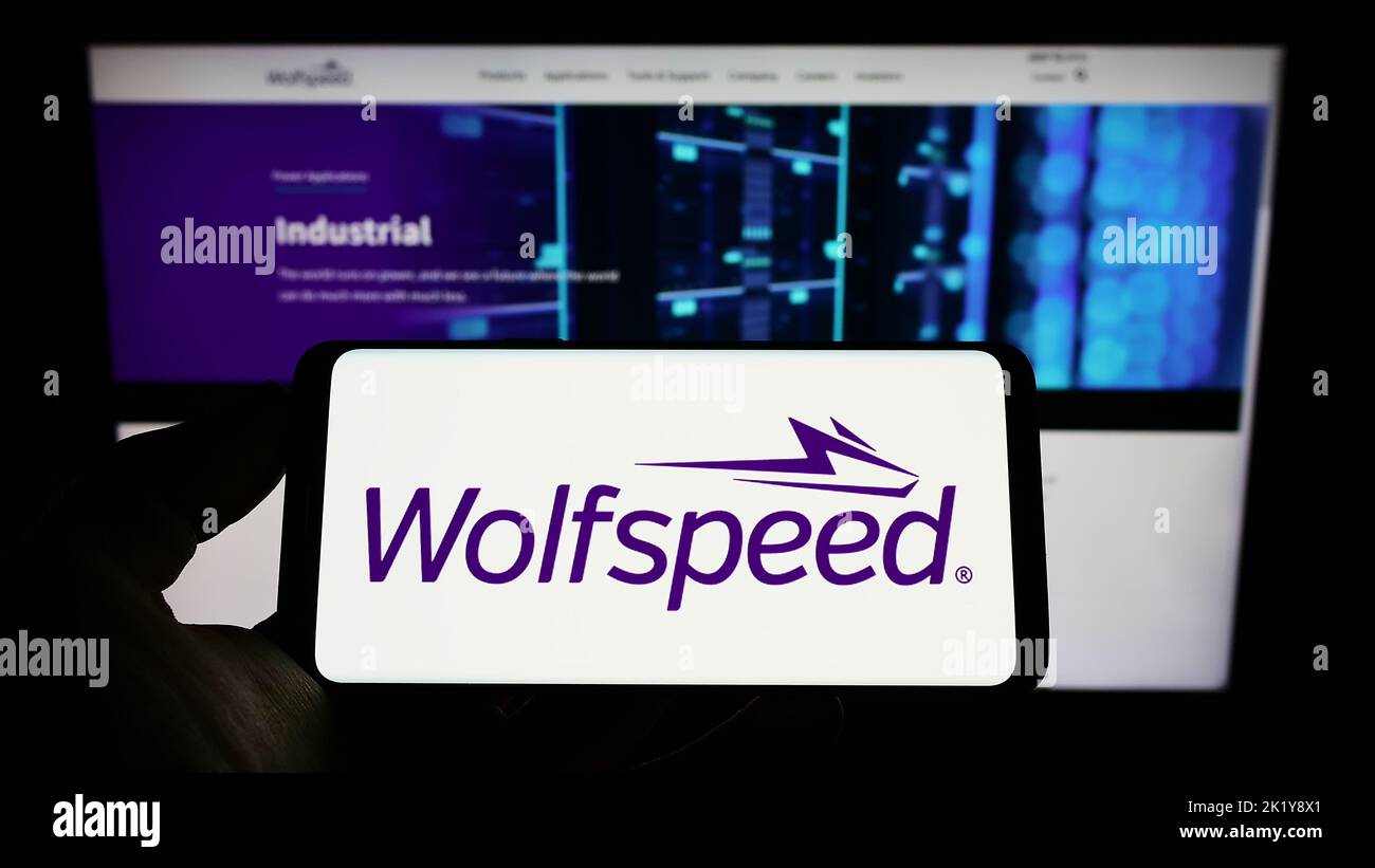 Personne tenant un smartphone avec le logo de la société américaine de semi-conducteurs Wolfspeed Inc. À l'écran devant le site Web. Mise au point sur l'affichage du téléphone. Banque D'Images