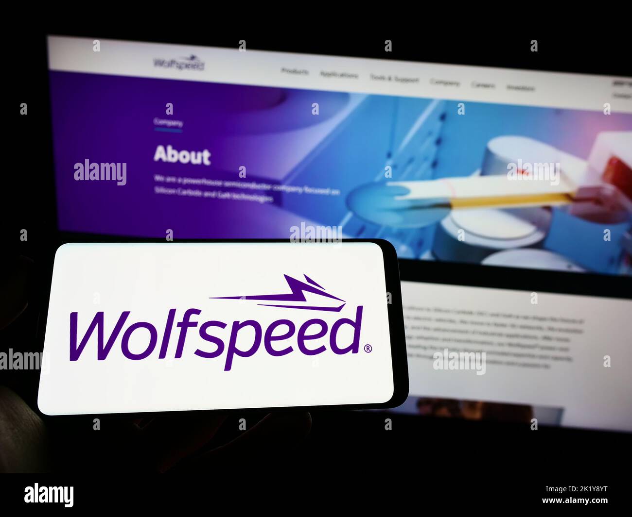 Personne tenant un téléphone portable avec le logo de la société américaine de semi-conducteurs Wolfspeed Inc. À l'écran en face de la page Web d'affaires. Mise au point sur l'affichage du téléphone. Banque D'Images