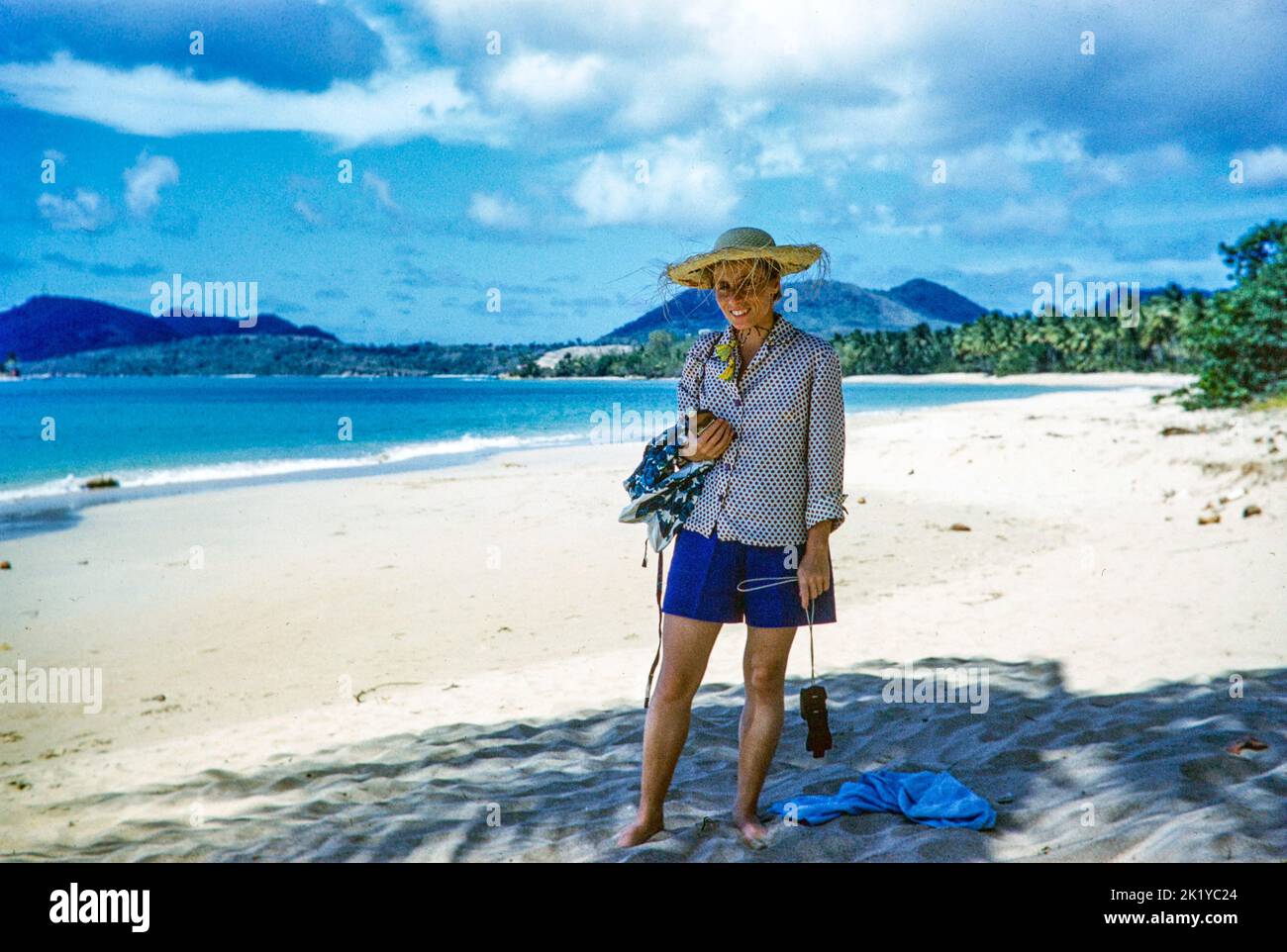 Touriste femelle portant un chapeau de paille sur la plage de sable de Vigie, Sainte-Lucie, Îles du vent, Antilles, 1962 Banque D'Images