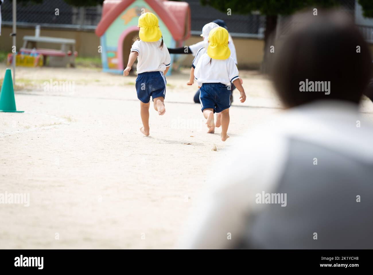 Les enfants qui s'exécutent sur le terrain pendant une journée de sport à une école maternelle japonaise Banque D'Images