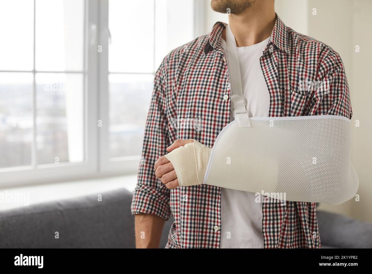 Un jeune homme qui a blessé son bras, sa main, son poignet et son coude porte un bandage et une élingue Banque D'Images