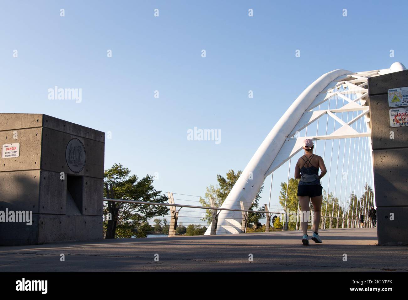 Une femme traverse le pont Humber Bay Arch en début de matinée par temps clair. Banque D'Images