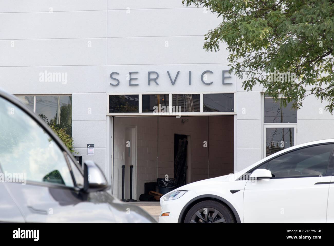 Un panneau d'entretien est visible au-dessus d'une entrée de garage d'un concessionnaire Tesla; les voitures garées, y compris un modèle X Tesla, sont à l'avant. Banque D'Images Un panneau d'entretien est visible au-dessus d'une entrée de garage d'un concessionnaire Tesla; les voitures garées, y compris un modèle X Tesla, sont à l'avant. Banque D'Images