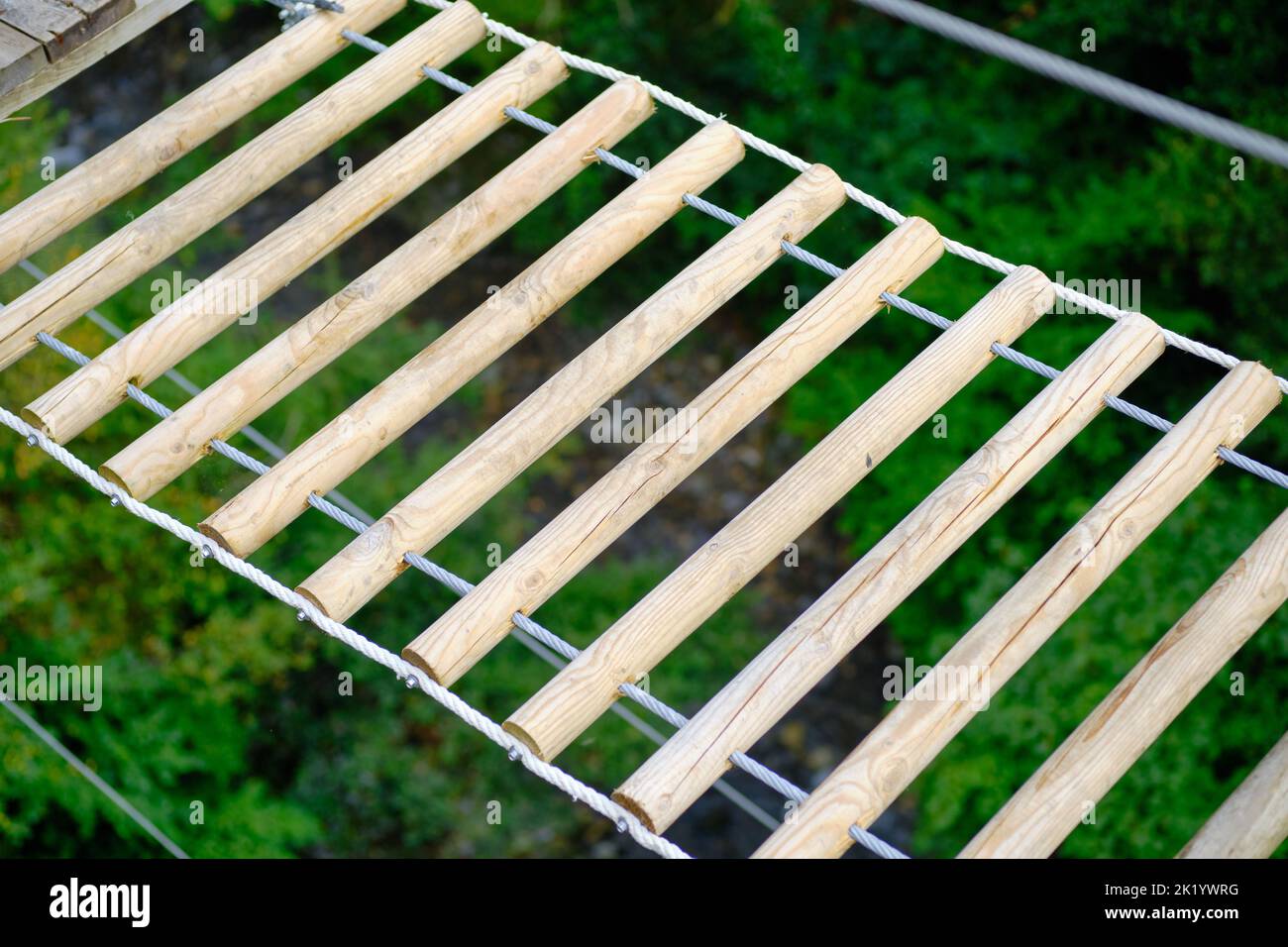 Vue rapprochée en grand angle d'un pont en bois d'un simple pont suspendu pour le passage de la rivière. Mise au point sélective. Forêt et rivière en arrière-plan. Banque D'Images