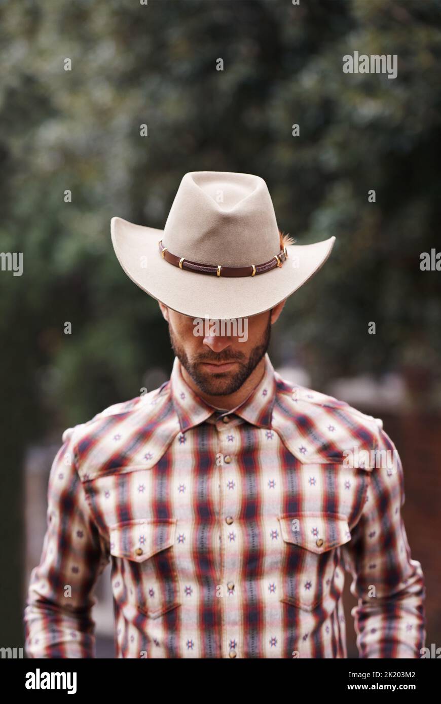 Couture de cowboy. Un beau homme portant une chemise à carreaux et un chapeau de cowboy Banque D'Images
