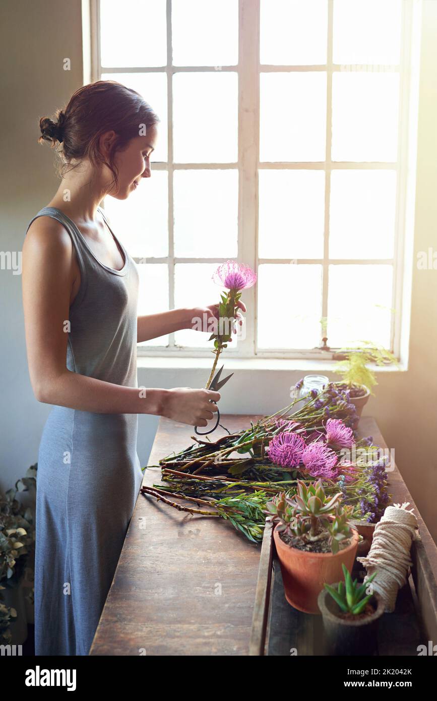 La créativité, c'est l'intelligence qui s'amuse. Un jeune fleuriste coupe des fleurs pour composer un bouquet Banque D'Images