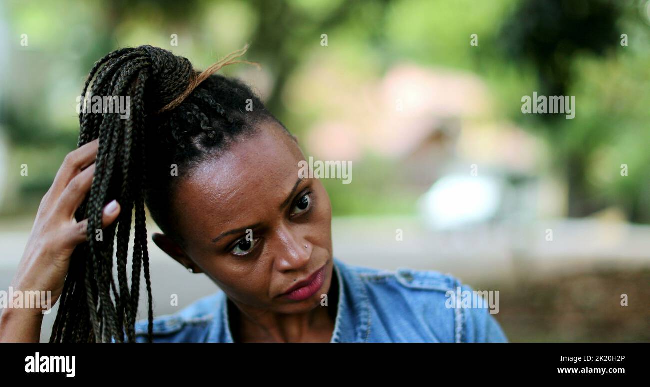 Femme africaine ajustant les cheveux de l'esure à l'extérieur Banque D'Images