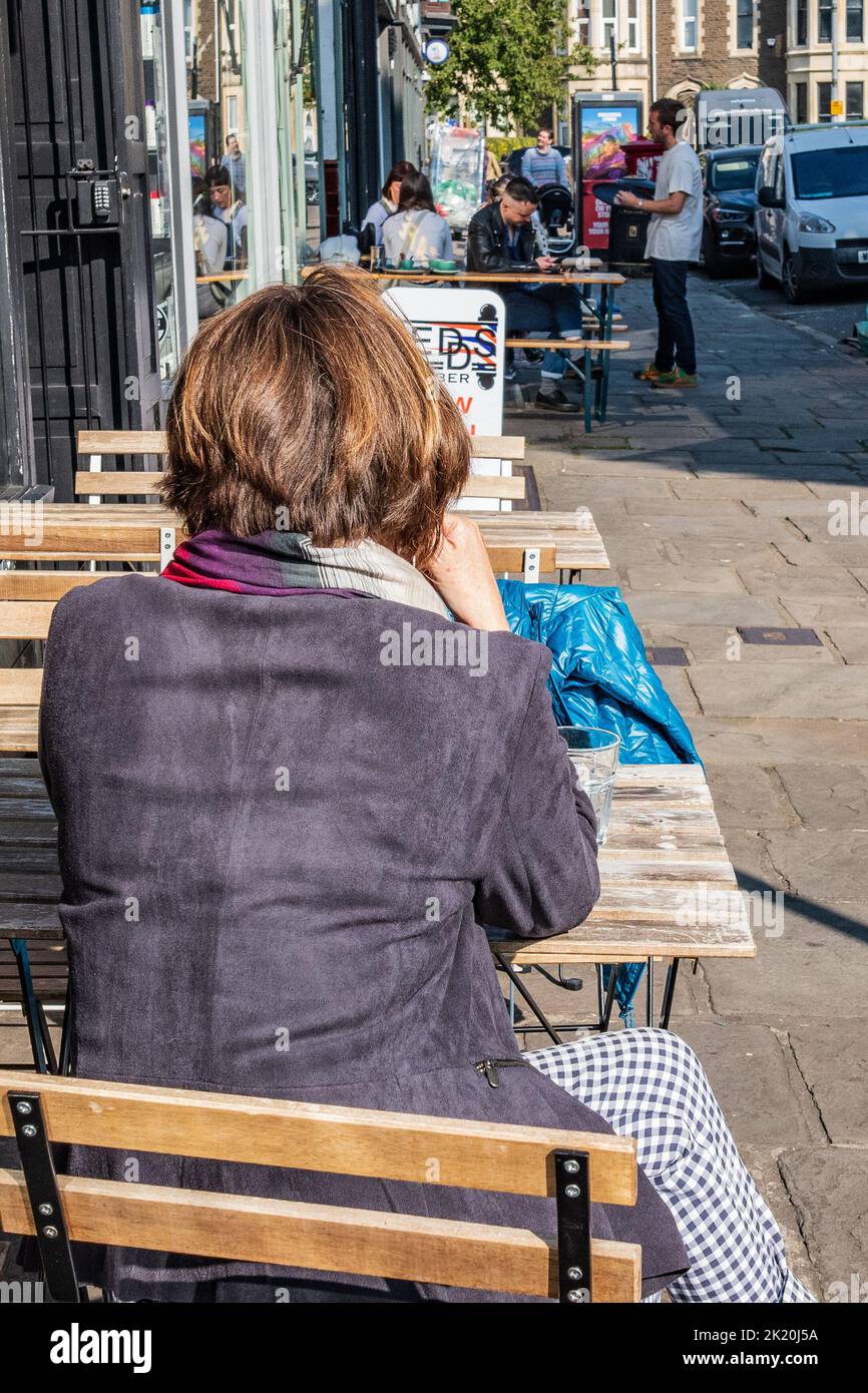Femme assise seule à l'extérieur d'un café attendant des amis à Cardiff, pays de Galles< Royaume-Uni Banque D'Images