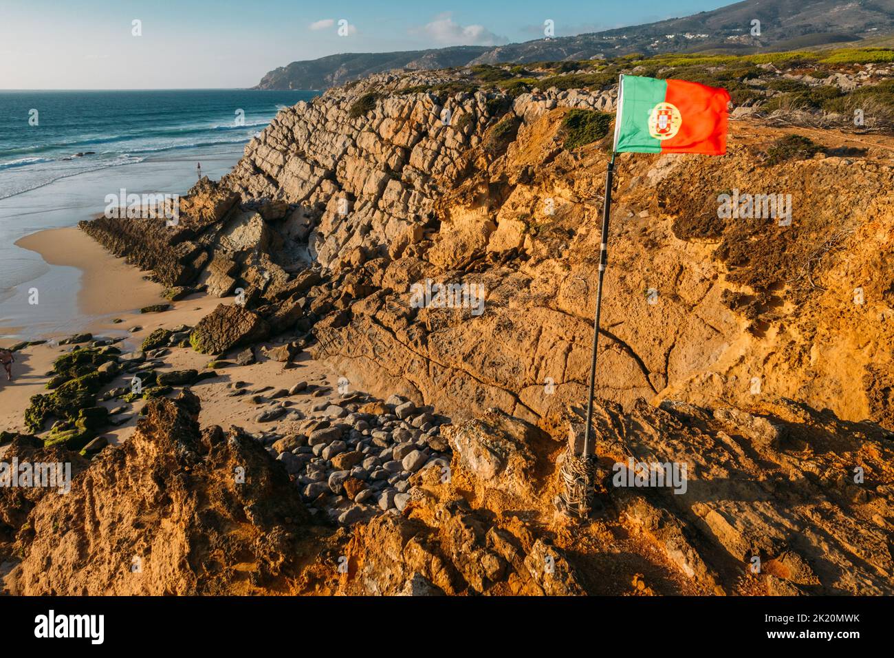 Brandir le drapeau portugais plus de ciel bleu et l'océan, la plage de Guincho, Portugal Banque D'Images