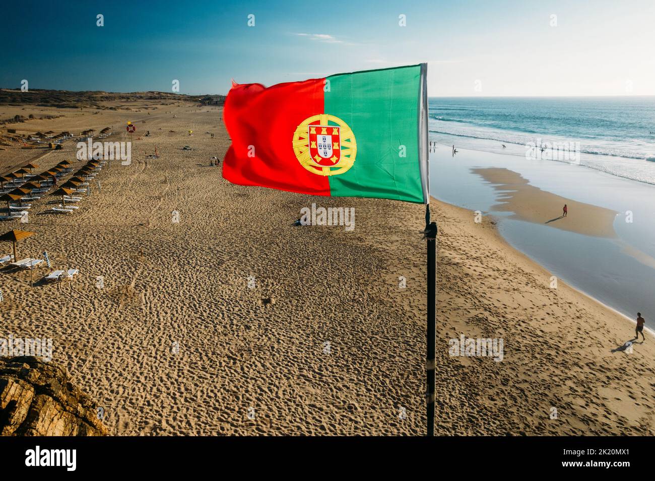 Brandir le drapeau portugais plus de ciel bleu et l'océan, la plage de Guincho, Portugal Banque D'Images