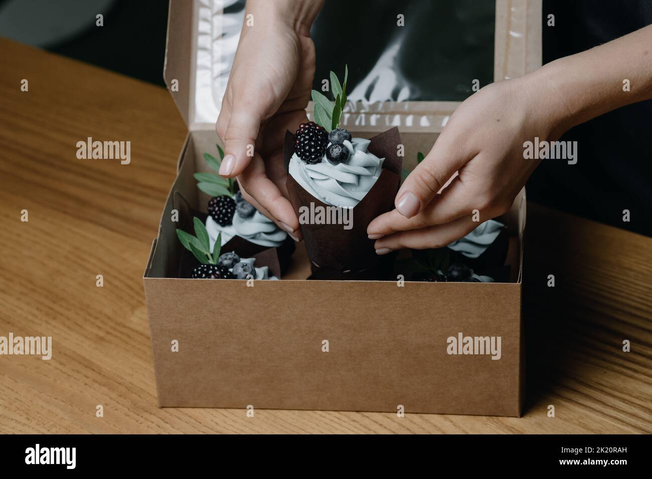Gros plan des mains des femmes mettant un cupcake dans une boîte Banque D'Images
