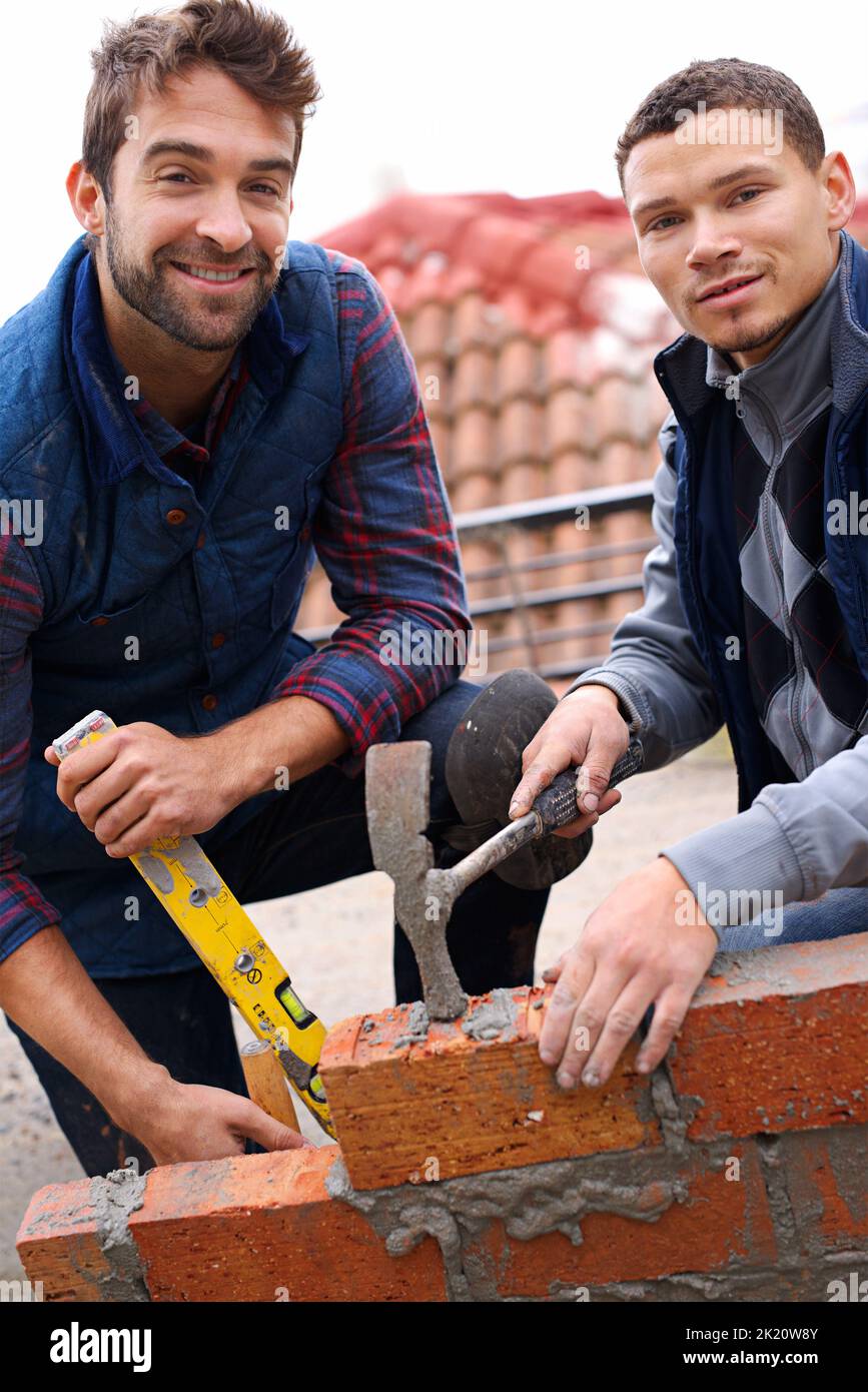 Ce mur sera fort. Portrait d'un bricklayer et de son apprenti au travail. Banque D'Images