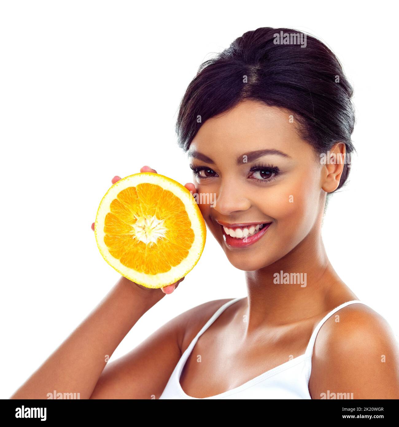 Bon pour ma peau. Une jeune femme en tenue de gymnastique tenant un orange et souriant à la caméra. Banque D'Images