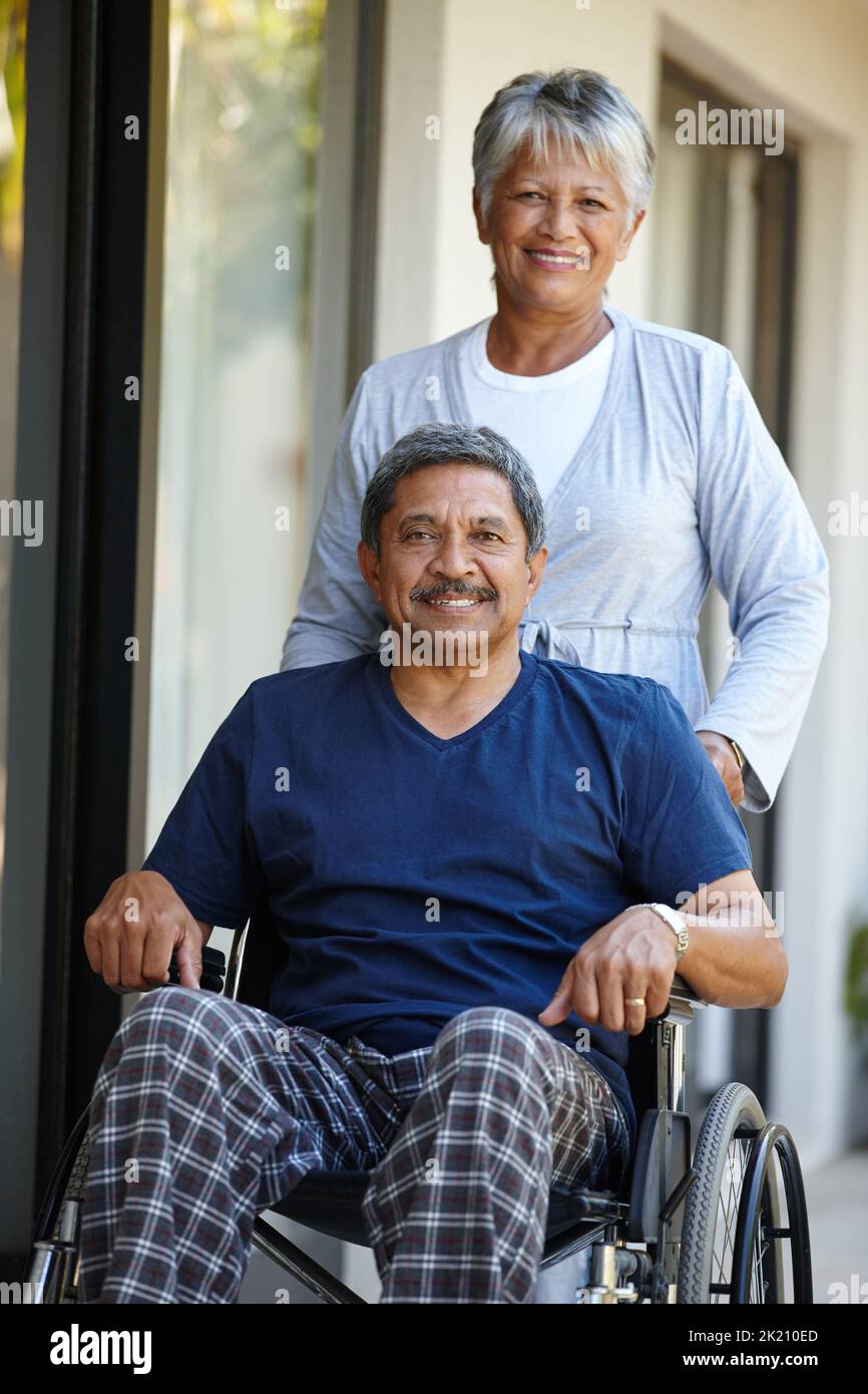 Shes mon rocher. Portrait d'une femme âgée poussant son mari dans un fauteuil roulant à l'extérieur. Banque D'Images