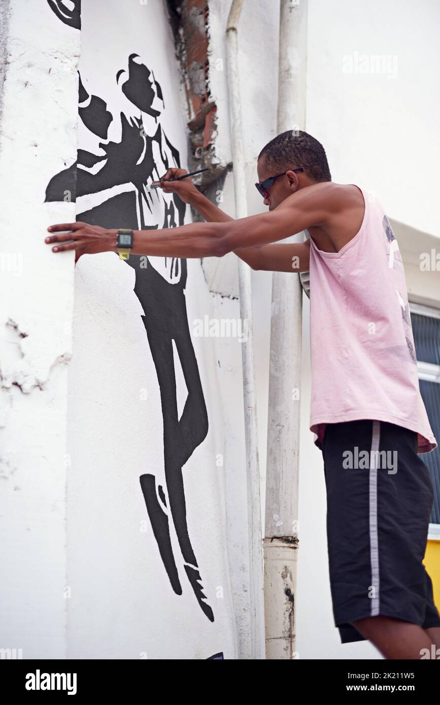S'exprimant par l'art un jeune graffiti artiste peindre un dessin sur un mur Banque D'Images