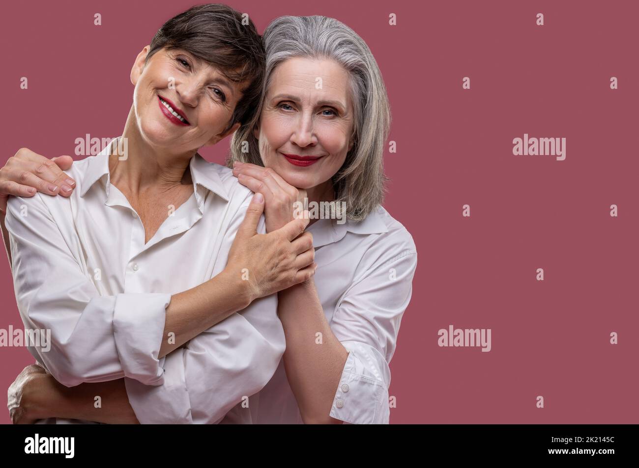 Deux jolies femmes matures debout ensemble et embrassant Banque D'Images