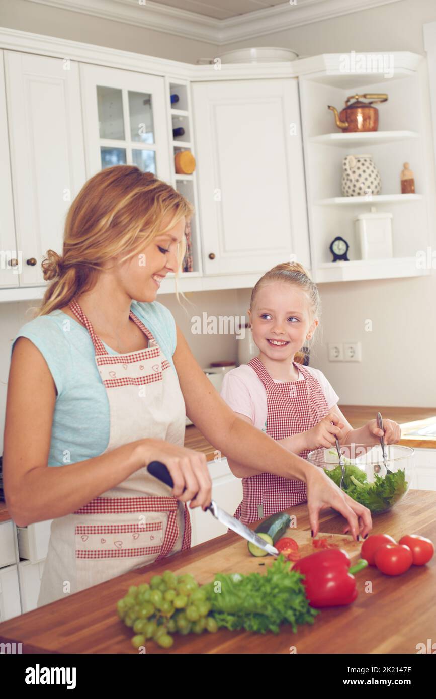 J'ai hâte de goûter cette salade. Une jeune mère et sa fille font une salade ensemble Banque D'Images