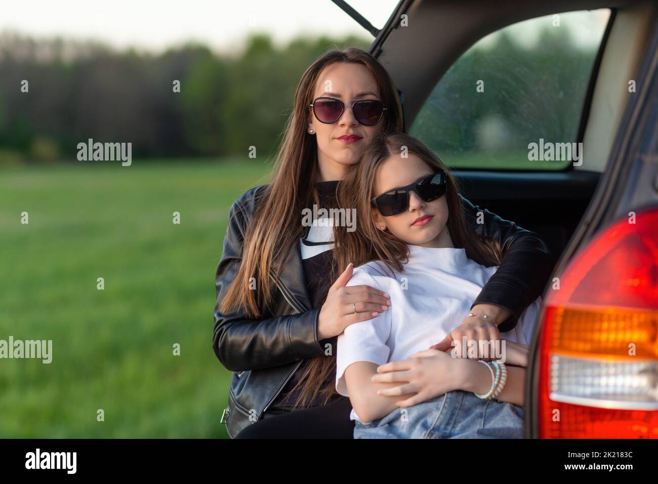 Mère et fille campant sur une colline et admirant le coucher du soleil tout en étant assis dans le coffre de voiture Banque D'Images