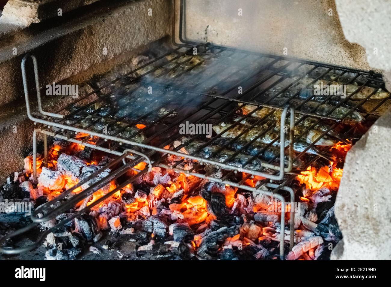Griller des sardines sur le feu de barbecue Banque D'Images