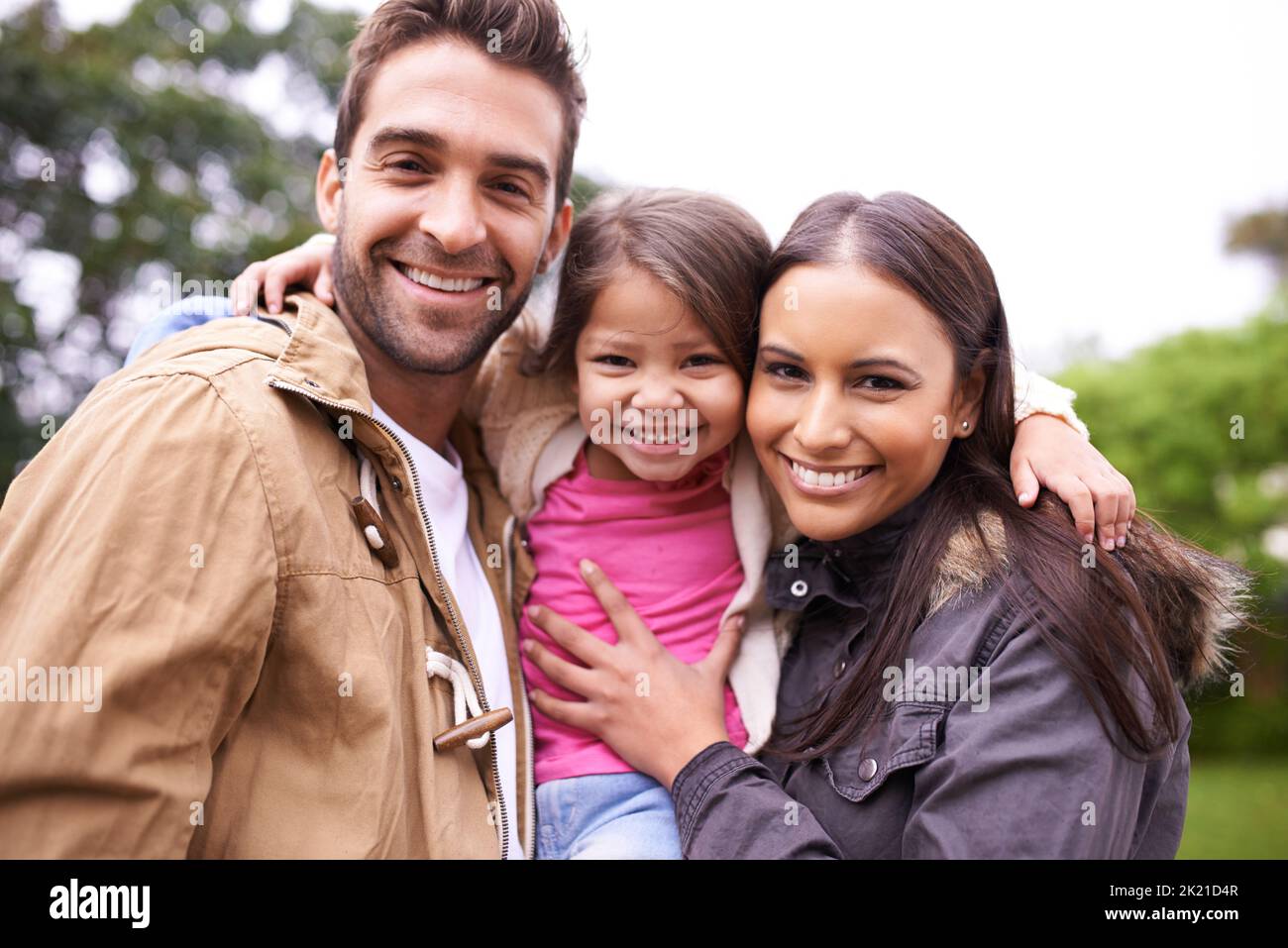 L'amour fait une famille. Un portrait court de deux parents heureux avec leur jeune fille debout à l'extérieur Banque D'Images