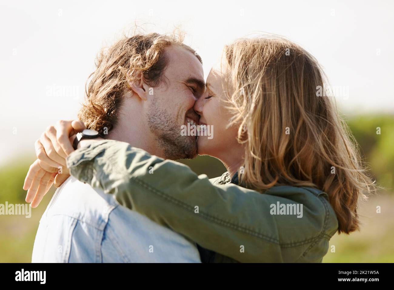 C'est du bonheur... un jeune couple affectueux qui partage un baiser dans la nature Banque D'Images