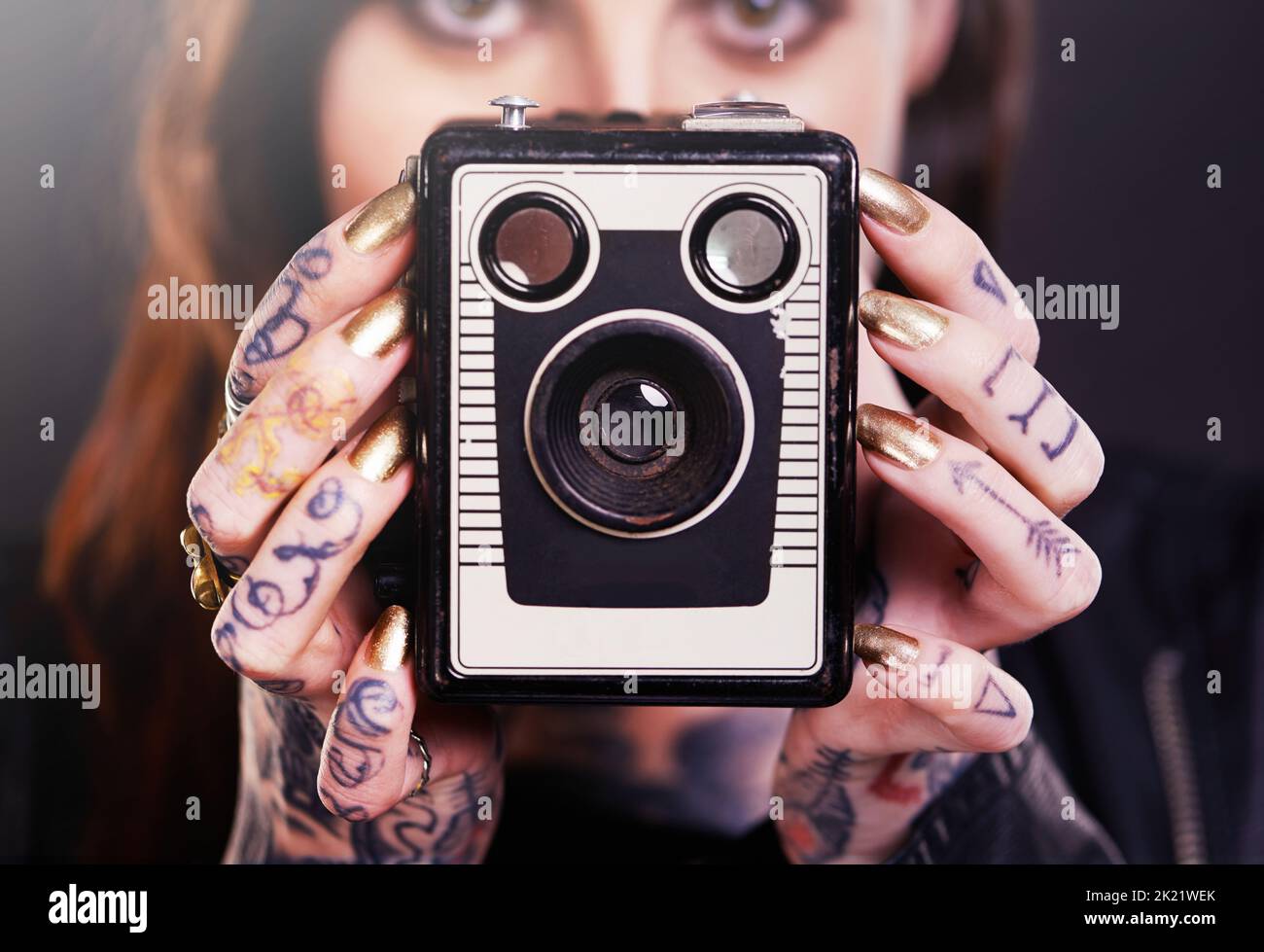 Rétro et alternative. Photo en studio d'une jeune femme tatouée portant un appareil photo d'époque Banque D'Images
