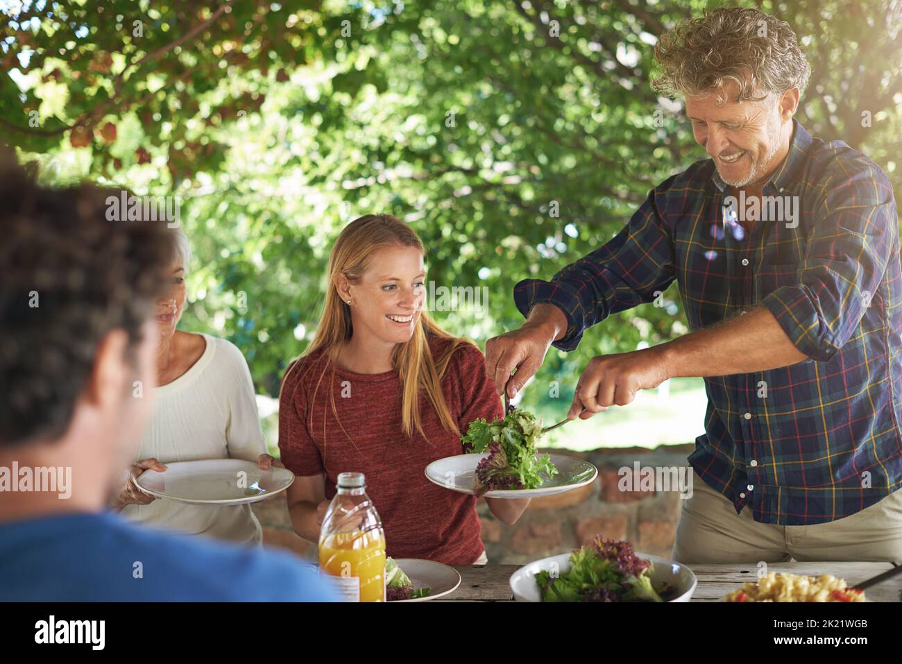 Qui veut de la salade. Une famille se préparant à manger le déjeuner ensemble à l'extérieur Banque D'Images