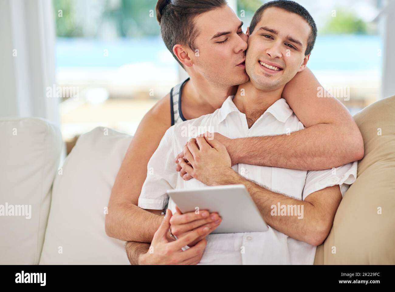 Nous ne pourrions plus être amoureux. Portrait d'un couple gay affectueux utilisant une tablette numérique tout en se relaxant sur le canapé à la maison Banque D'Images