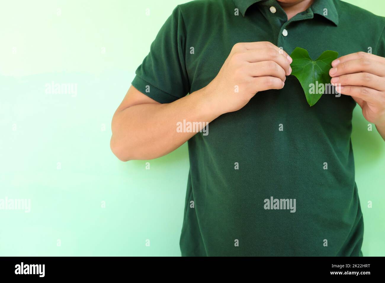 Un cœur sain, un amour pour l'environnement et un concept de conservation de l'environnement. Jeunes hommes asiatiques mains tenant une feuille en forme de coeur vert en haut à gauche Banque D'Images