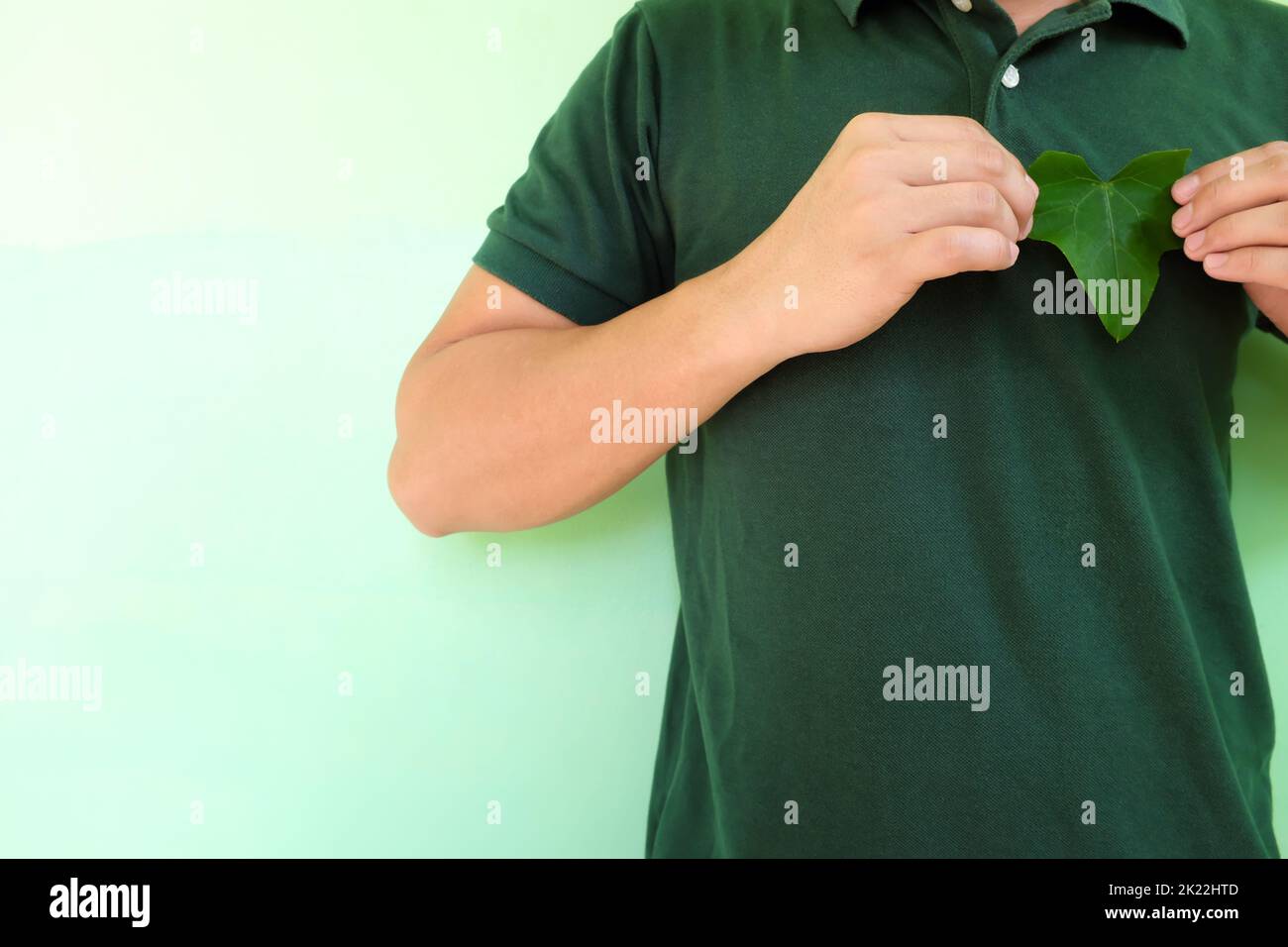 Un cœur sain, un amour pour l'environnement et un concept de conservation de l'environnement. Jeunes hommes asiatiques mains tenant une feuille en forme de coeur vert en haut à gauche Banque D'Images