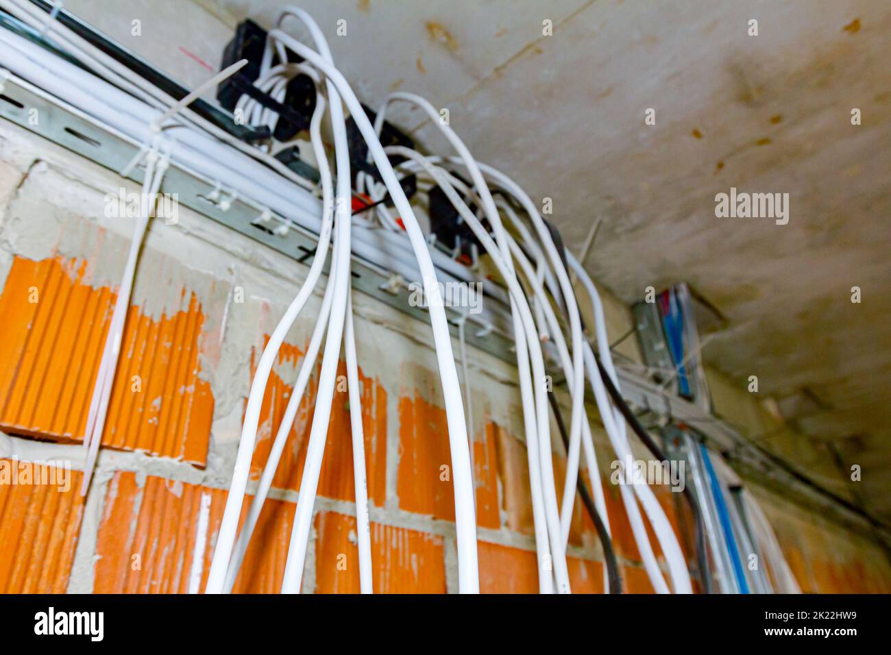 Les câbles sont suspendus au plafond du bâtiment en cours de construction, travaux en cours. Positionnement des fils et des câbles électriques. Banque D'Images