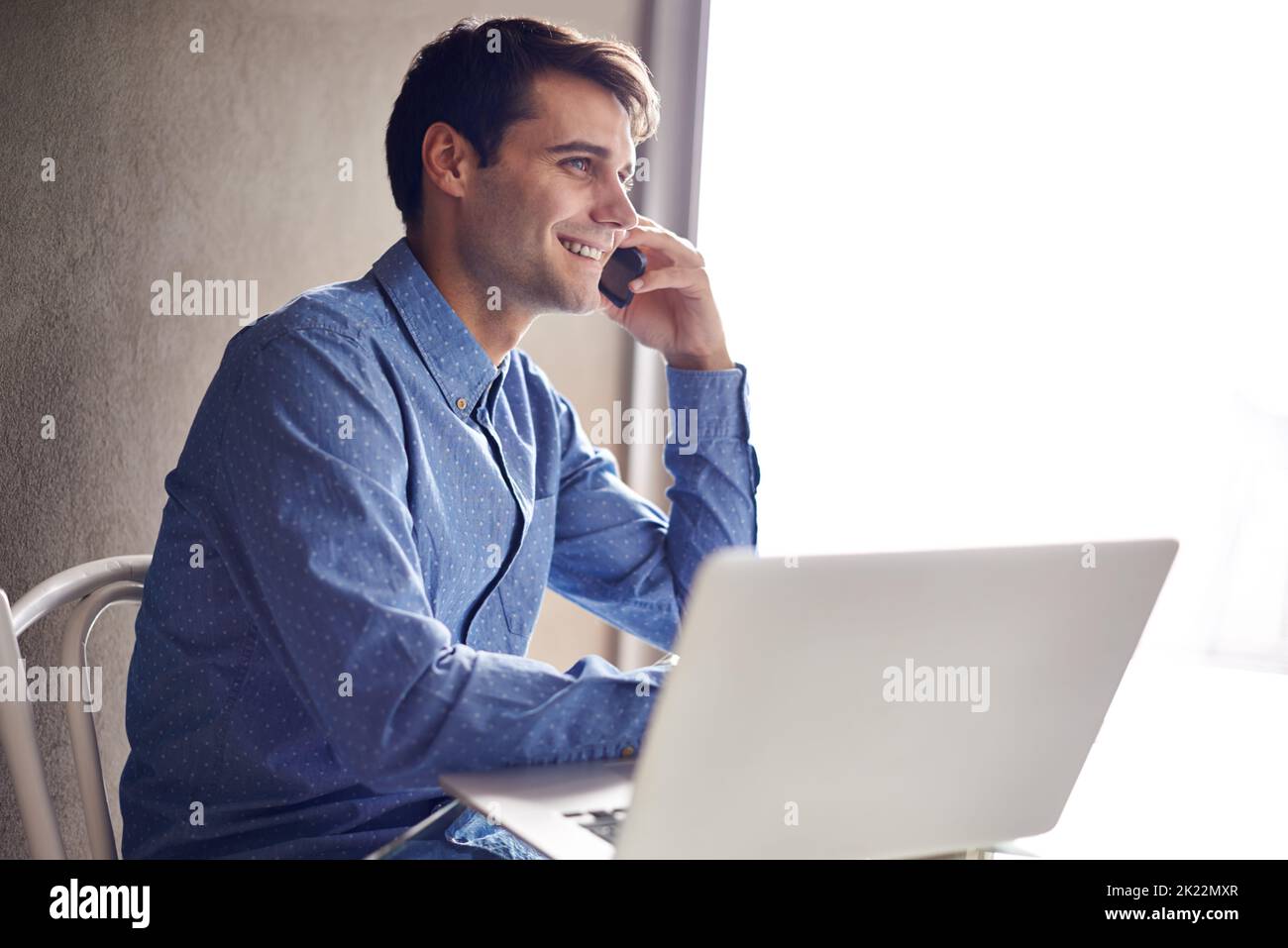 Rattraper un client. Un jeune homme d'affaires confiant parlant au téléphone tout en étant assis à son bureau Banque D'Images