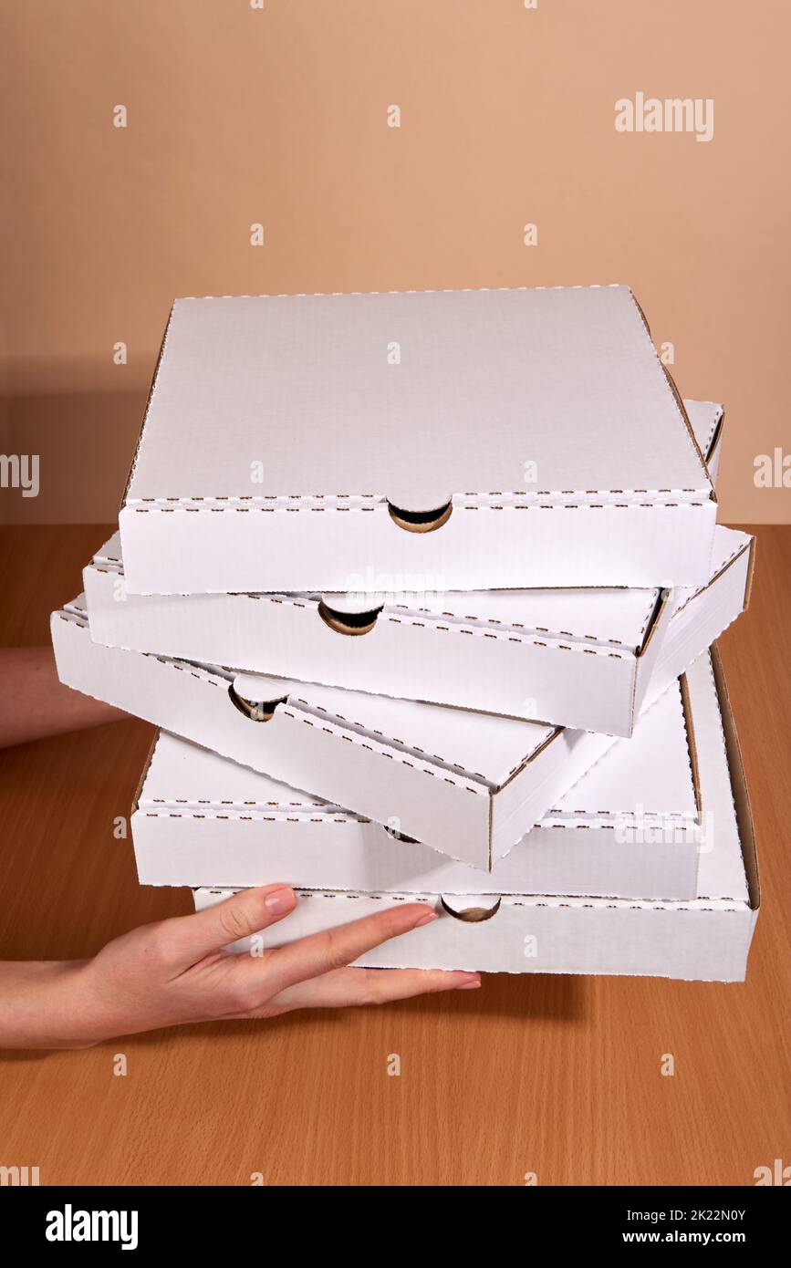 Mains étirant les boîtes avec livraison de pizza à domicile Banque D'Images