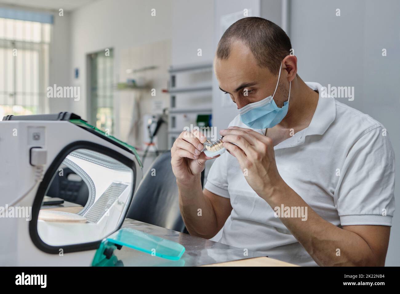 Dentiste moulins à main couronnes de dent créées sur 3D imprimante pour métal. Technicien dentaire travaillant avec des couronnes en céramique dans une boîte de protection au laboratoire. Banque D'Images