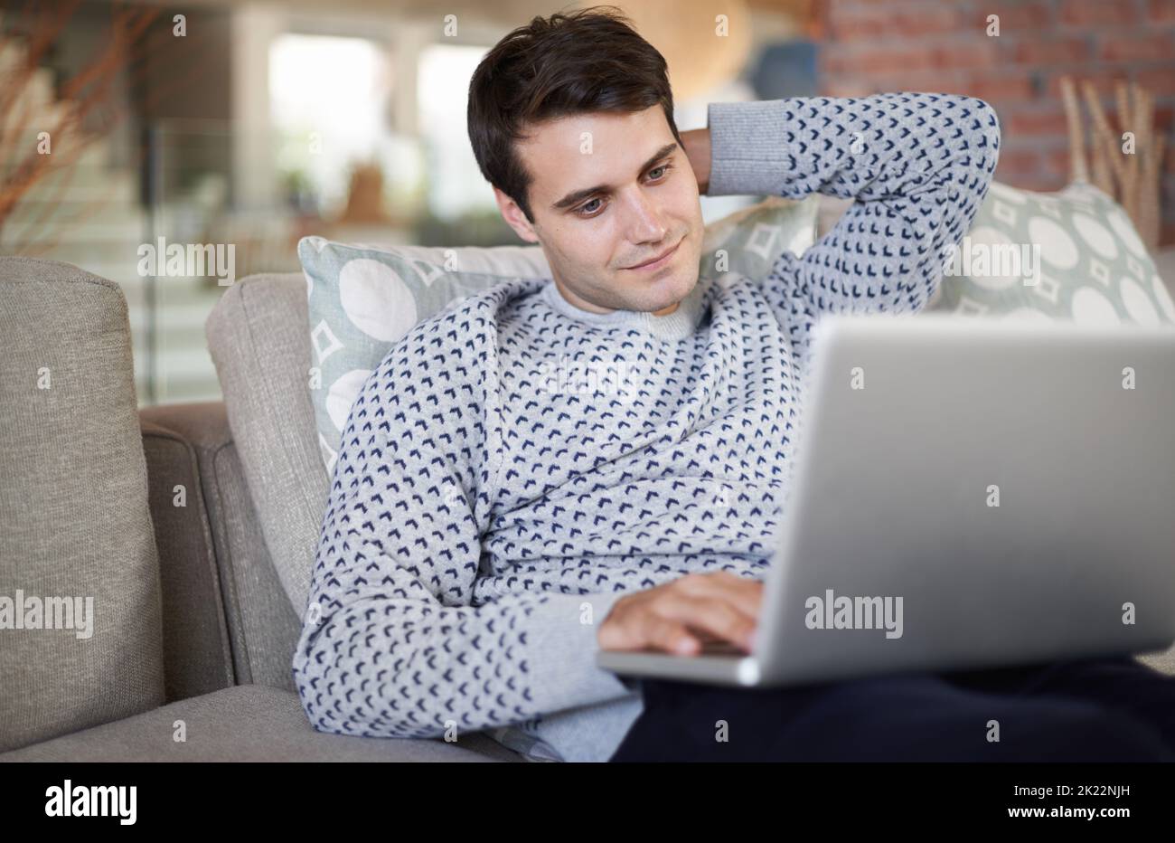 Un homme qui se détend dans son salon tout en utilisant son ordinateur portable Banque D'Images
