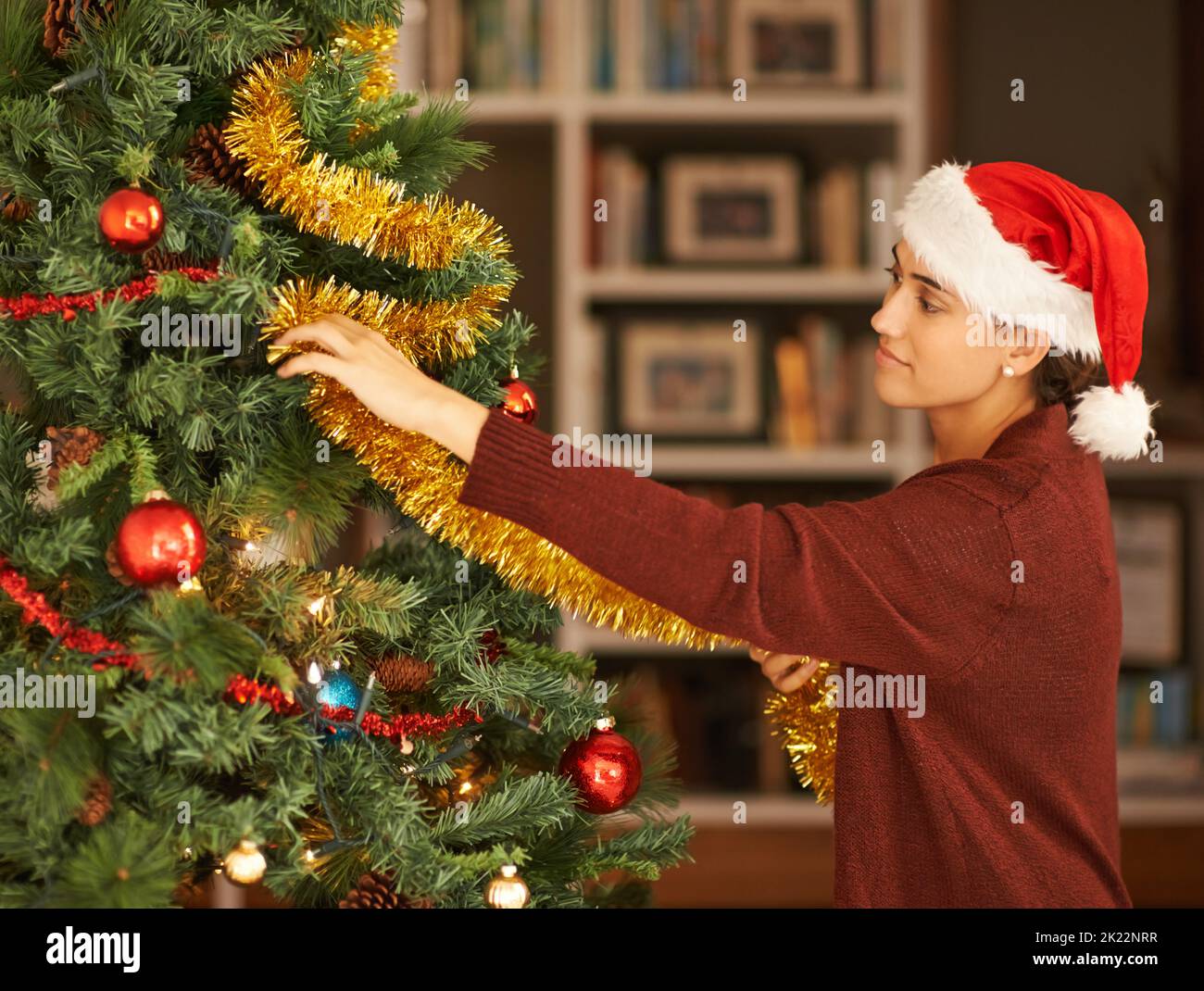 Faire des vacances un moment festif. Une jeune femme attrayante décorant son arbre de Noël Banque D'Images