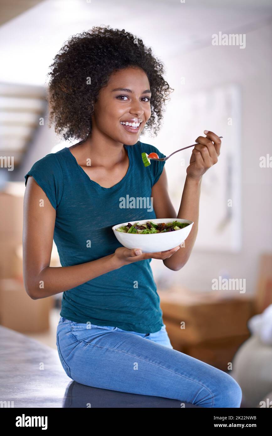Shes aimant son nouveau régime. Une belle jeune femme mangeant un bol de salade à la maison Banque D'Images