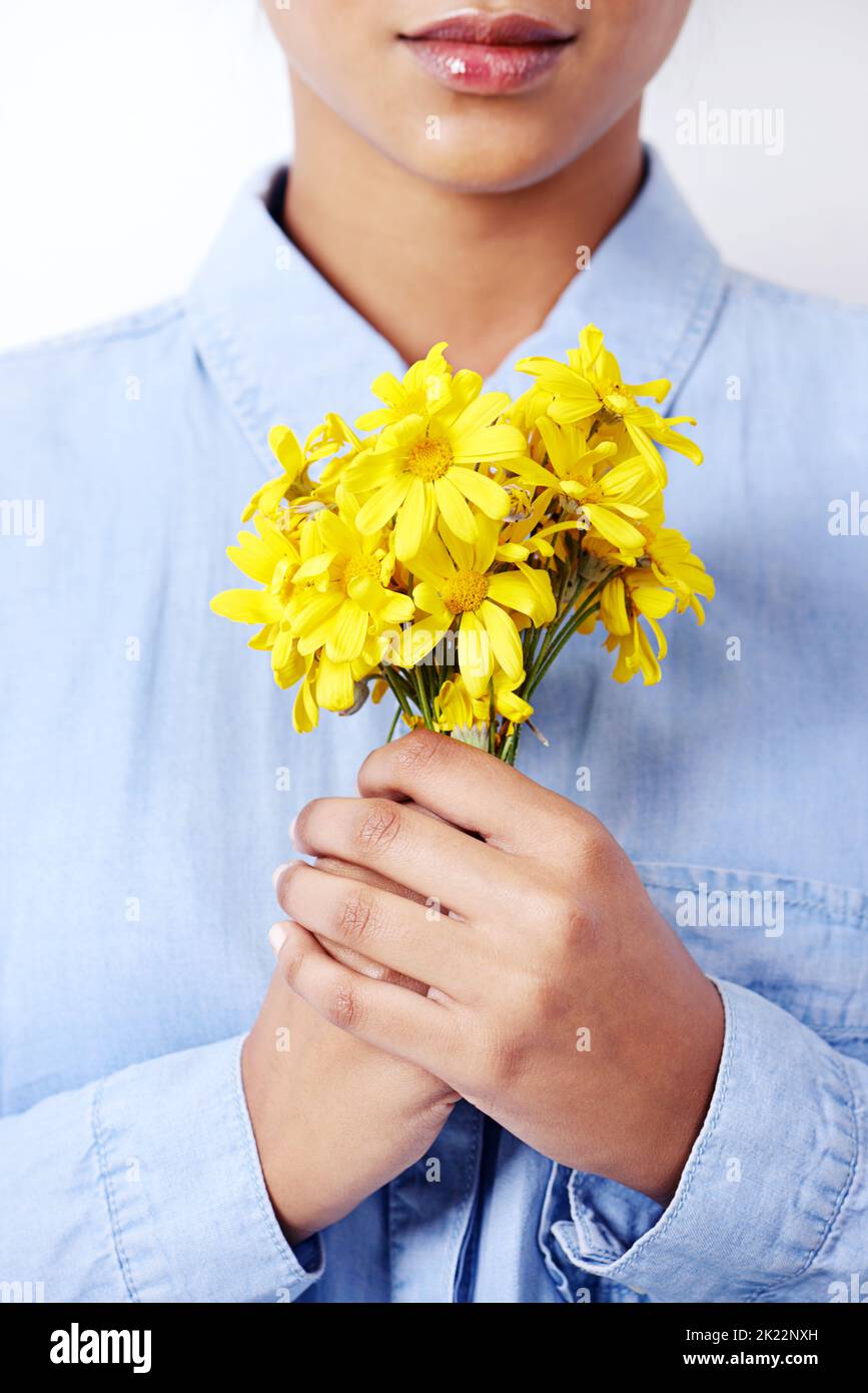 Aussi délicats que ces pétales. Studio photo d'une jeune femme ethnique attrayante tenant un bouquet de fleurs. Banque D'Images