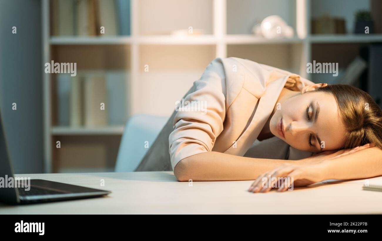 Étude de nuit. Fatigue de travail. Une étudiante en sommeil paisible et fatiguée, équipée d'un ordinateur portable ouvert, allongé sur un bureau au lieu de travail. Banque D'Images
