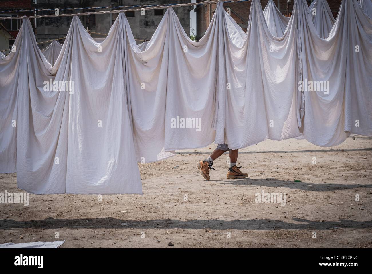 Un homme marchant derrière des feuilles blanches sécher à Katmandou, Népal Banque D'Images
