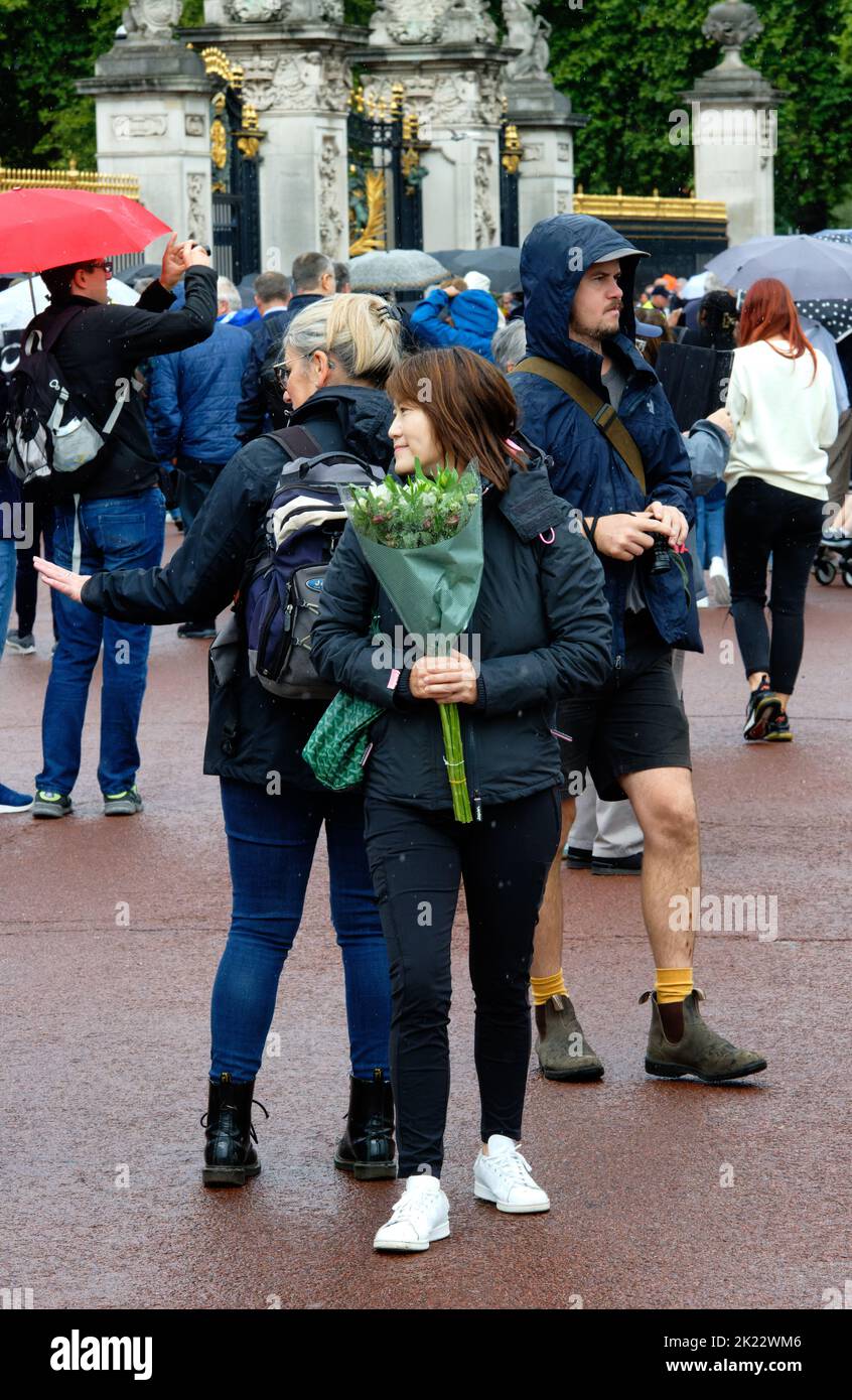 Pleurer portant un bouquet de fleurs au commerce de la reine Elizabeth II après sa mort, Buckingham Palace, Londres Banque D'Images