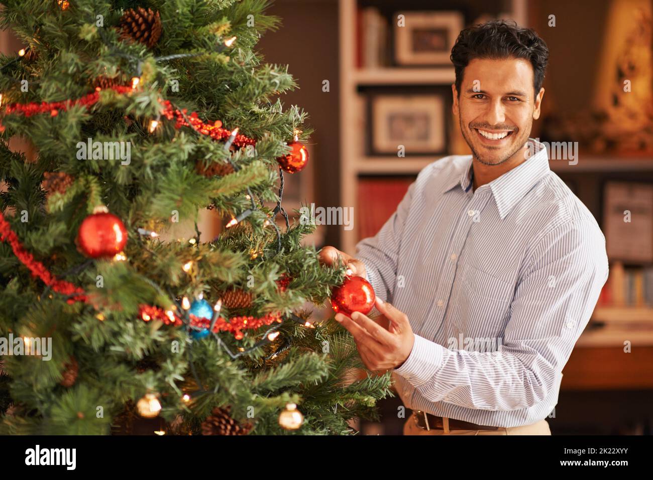 Chef en charge des décorations d'arbre de noël. Un jeune homme décorant son arbre de noël Banque D'Images