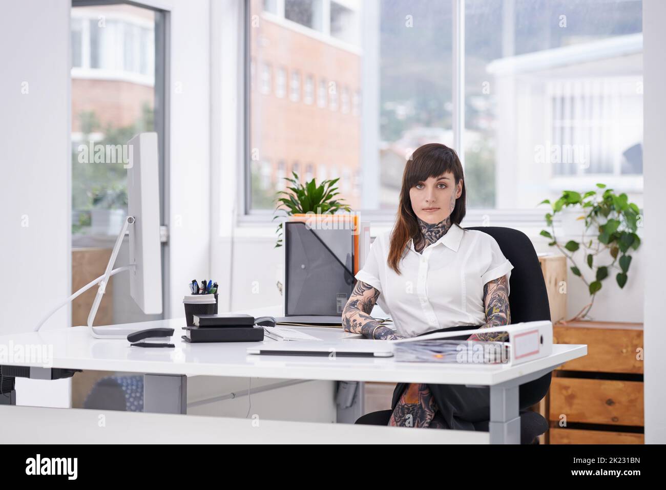 Exercice de l'expression individuelle. Une photo d'une femme d'affaires tatouée assise à son bureau. Banque D'Images