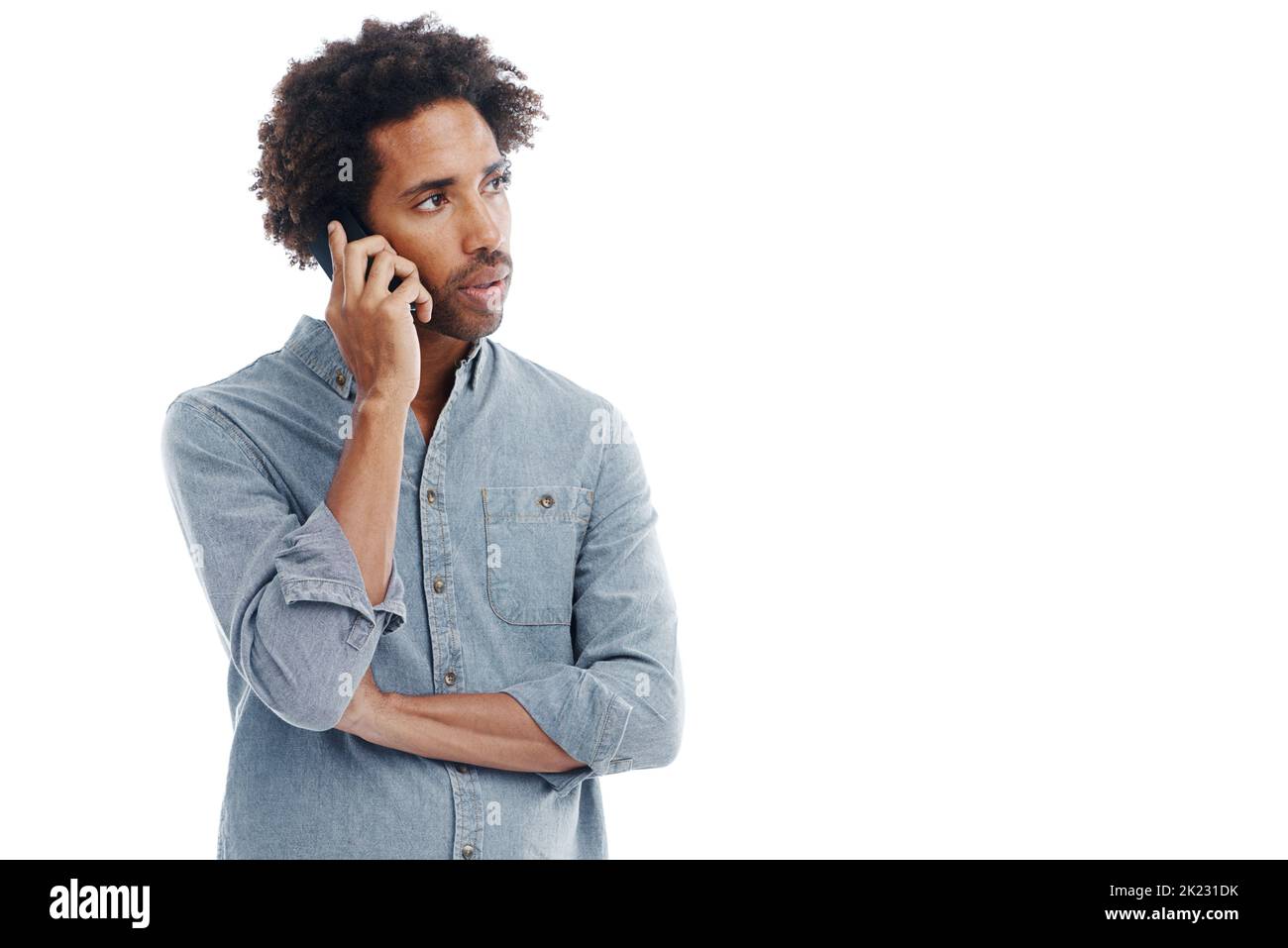 Je ne suis pas sûr que j'aime ce que j'entends par la messagerie instantanée. Studio photo d'un beau homme parlant sur son téléphone portable isolé sur blanc. Banque D'Images