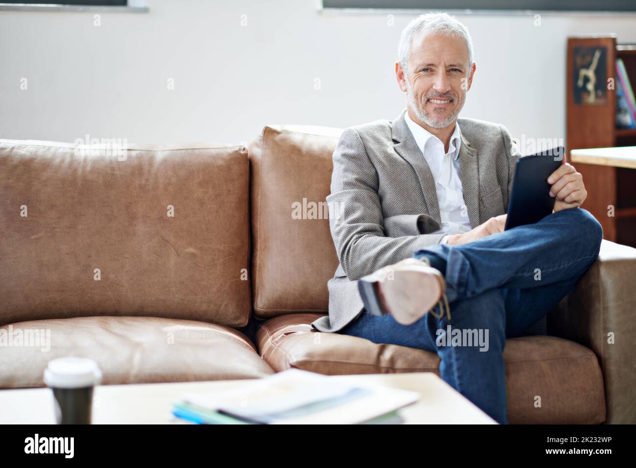 Temps de repos et de détente. Portrait d'un homme mûr se détendant avec sa tablette numérique dans son salon. Banque D'Images