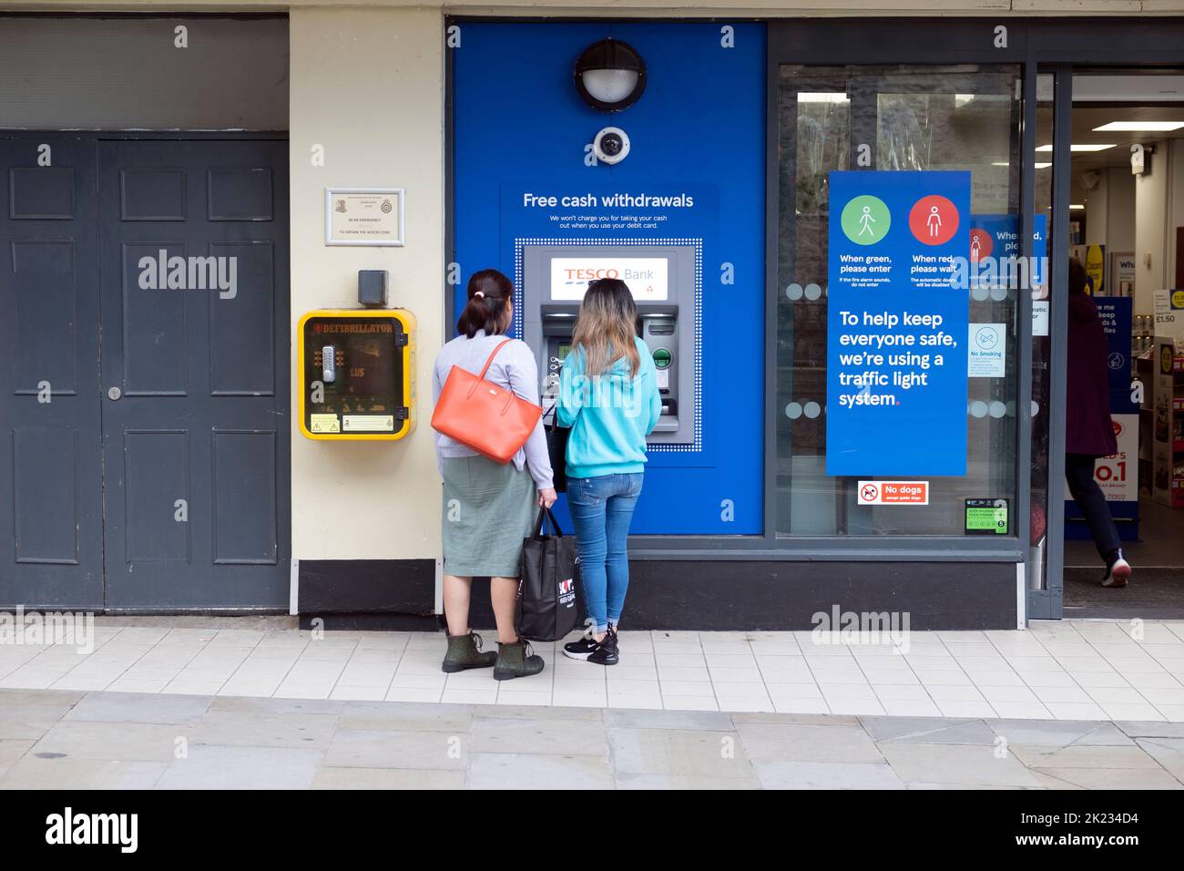 Vue extérieure de la boutique Tesco Extra clients les gens qui utilisent un distributeur automatique de billets à l'extérieur de l'épicerie à Tenby Pembrokeshire South Wales UK Banque D'Images